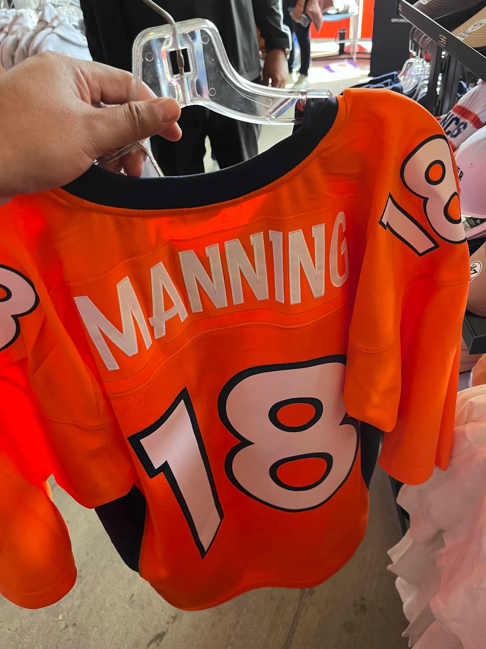 Jersey naranja de Peyton Manning con el número 18 colgado de un gancho