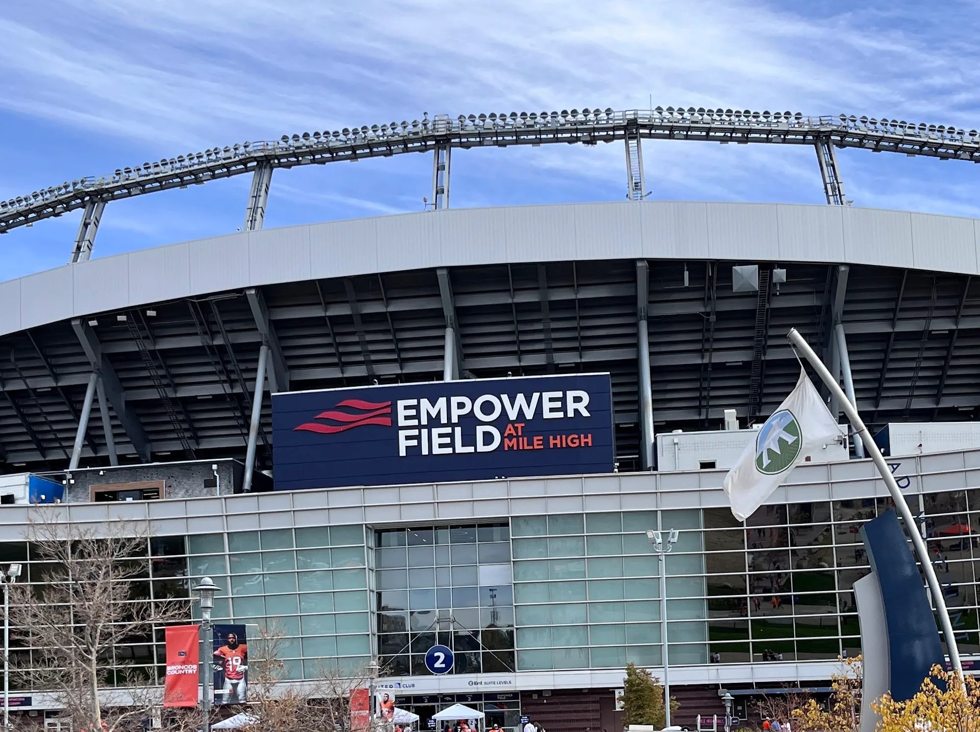 Fachada de Empower Field at Mile High bajo un cielo azul, con el letrero del estadio al centro